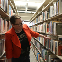 student choosing a book from library shelf